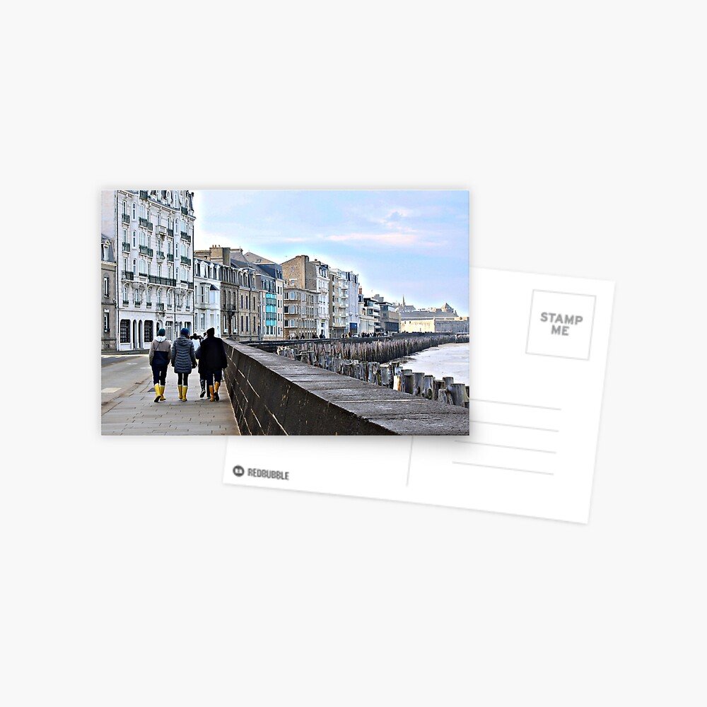 People walking along Saint-Malo seawall with historic buildings and low tide coastline in Brittany France