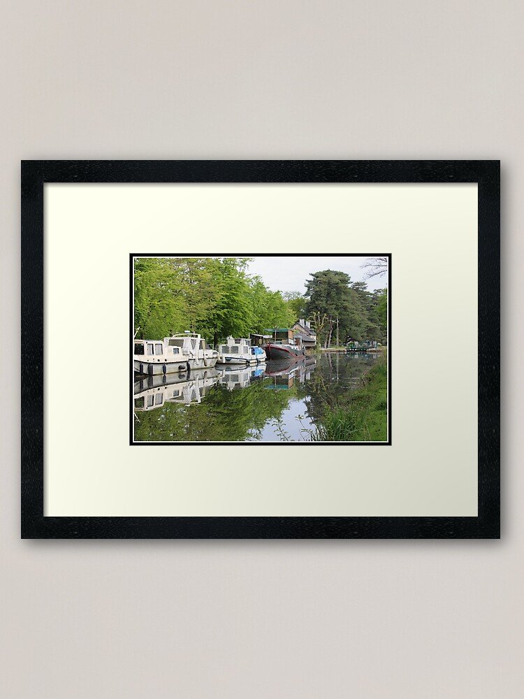 Boats moored along the Oust River in Malestroit Brittany with reflections and green trees